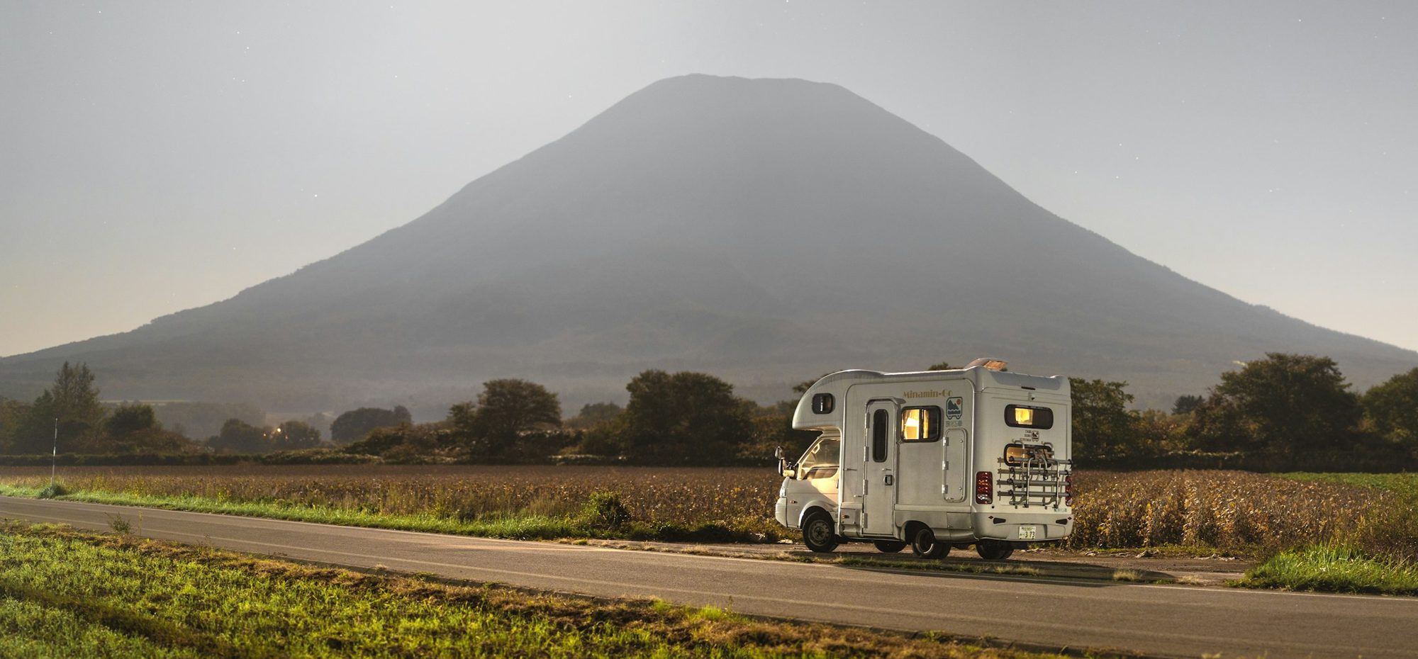 Een camper op een weg naar een vulkaan, bij zonsopgang